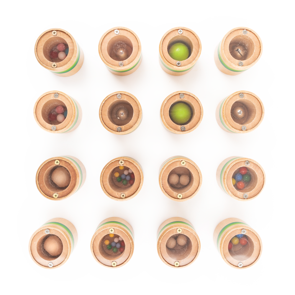 Draufsicht auf 16 runde Holzbehälter mit verschiedenfarbigen Kugeln im Inneren, rasterförmig angeordnet – perfekt für ein Hör-Memo-Gedächtnisspiel im charmanten Raupe Nimmersatt-Design.