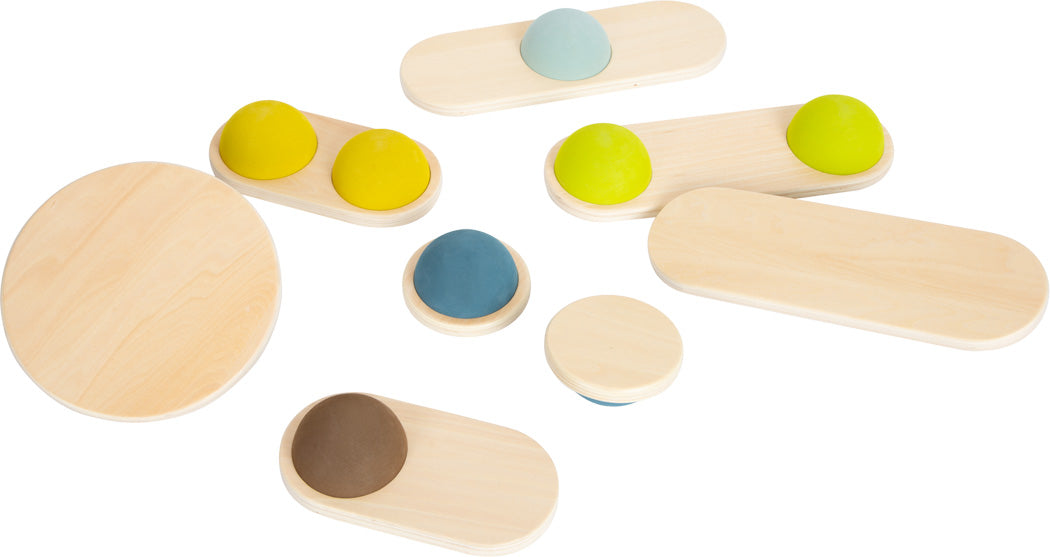 Balancebretter und -scheiben aus Holz mit bunten Gummikuppeln auf der Oberseite, sogenannte Balanciersteine, sind auf einem weißen Hintergrund angeordnet und helfen, den Gleichgewichtssinn und die Koordination zu verbessern.
