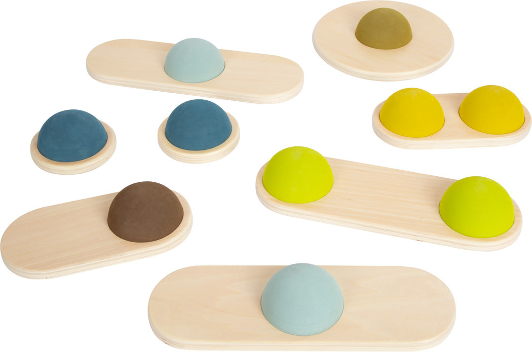 Neun Holzbretter mit abgerundeten, kuppelförmigen Noppen in verschiedenen Farben helfen Kindern auf weißem Untergrund, ihre Koordination zu verbessern und ihren Gleichgewichtssinn zu entwickeln.
