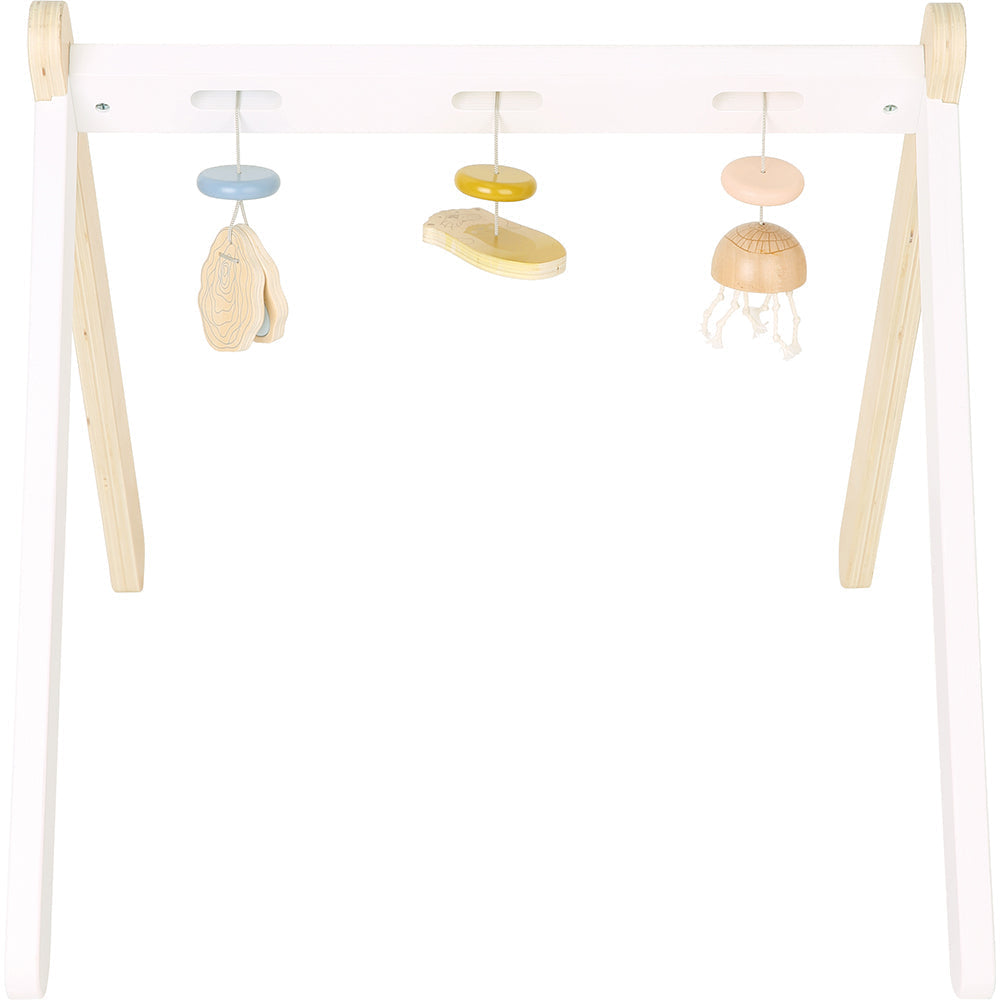 Holz Baby-Spielbogen mit drei motorikfördernden Hängespielzeugen in Blau, Gelb und Beige auf einem weißen und naturfarbenen Holzgestell.