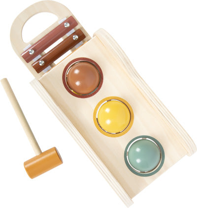 Dieses hölzerne Klopfspiel besteht aus drei farbigen Bällen und einem Hammer und bietet Motorikspaß, wenn Kinder die Bälle durch die Löcher hämmern.