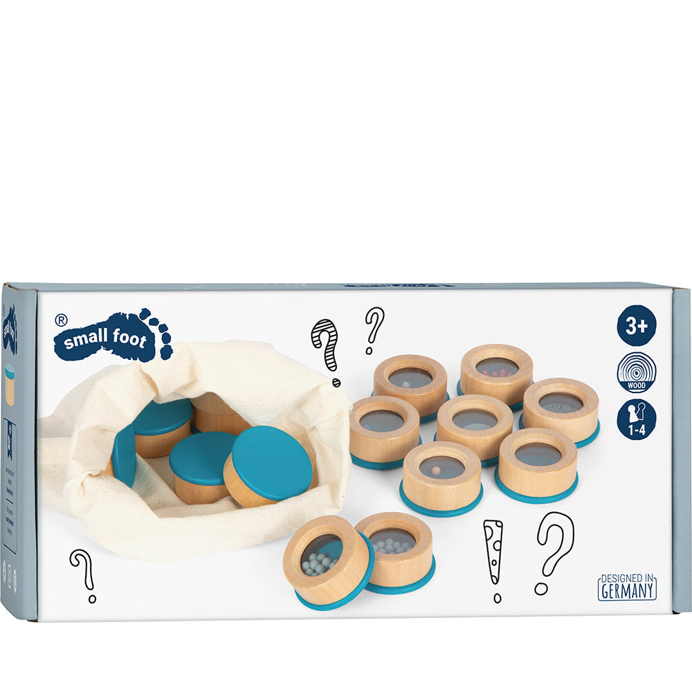 Box mit hölzernen Sinnesspielsteinen, teilweise mit Spiegeln, und einem Stoffbeutel, konzipiert für Sinnesspiele, um Kindern ab 3 Jahren dabei zu helfen, Klangunterschiede zu entdecken und die auditiven Fähigkeiten zu stärken.