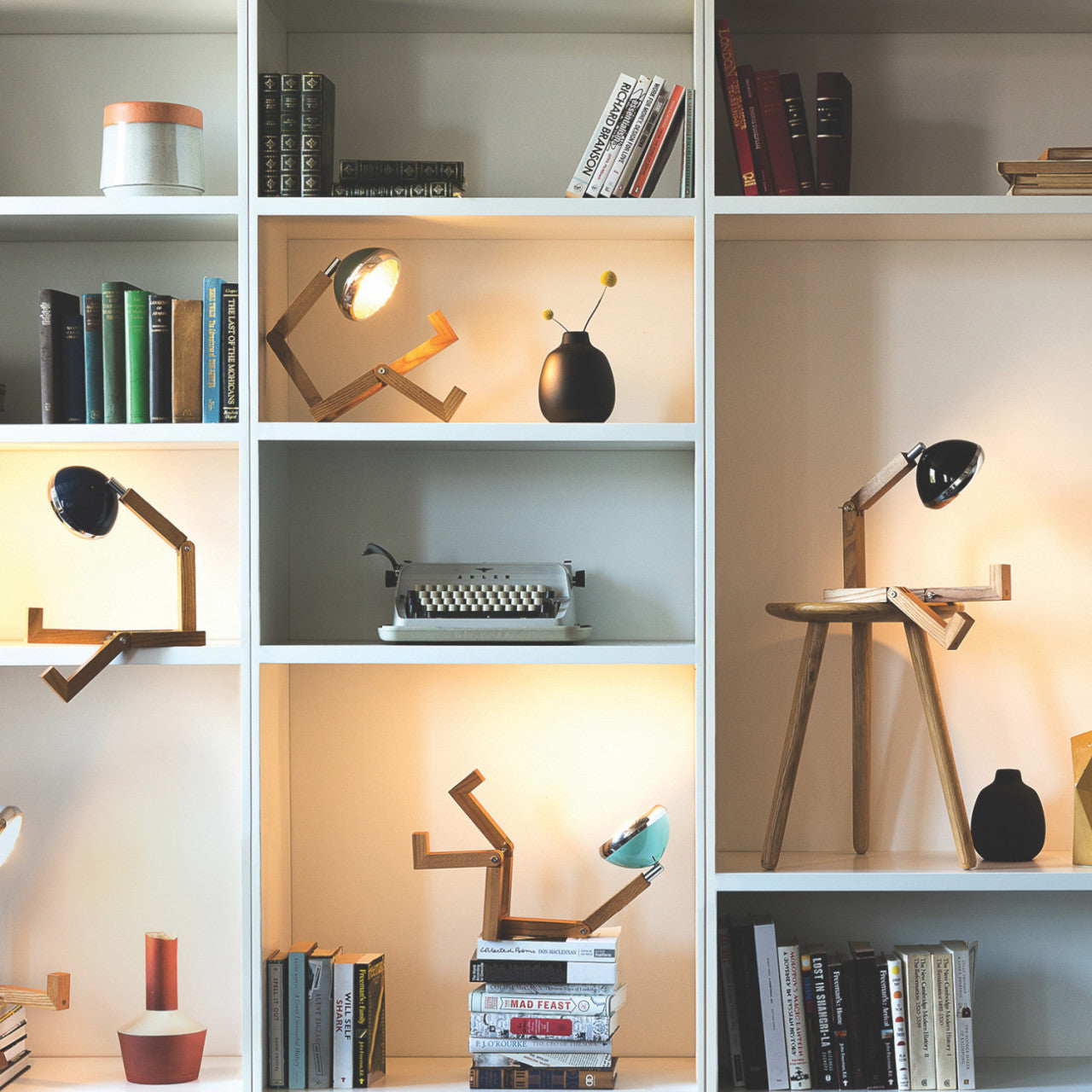 Modernes Bücherregal mit Büchern, Tischlampen, einer Schreibmaschine und Deko-Objekten auf weißen Regalböden aus edlem Eschenholz. Inklusive flexibler Gelenke zur einfachen Verstellung der Regalböden.