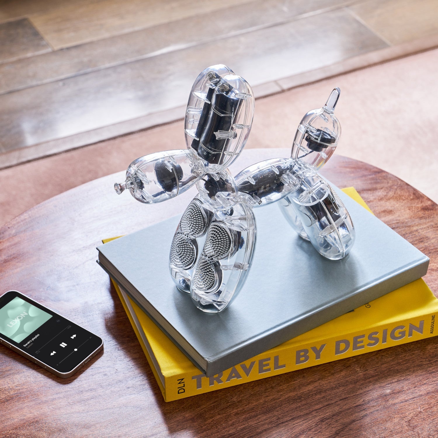 Balloon Dog Lautsprecher von Jeff Koons - Acryl sitzt auf Büchern neben einem Smartphone.