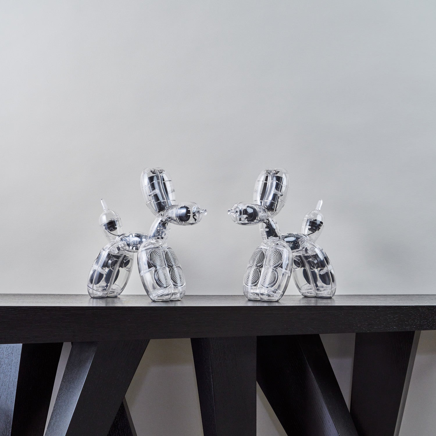 Zwei glänzende Balloon Dog Lautsprecher von Jeff Koons auf einem dunklen, modernen Tisch.