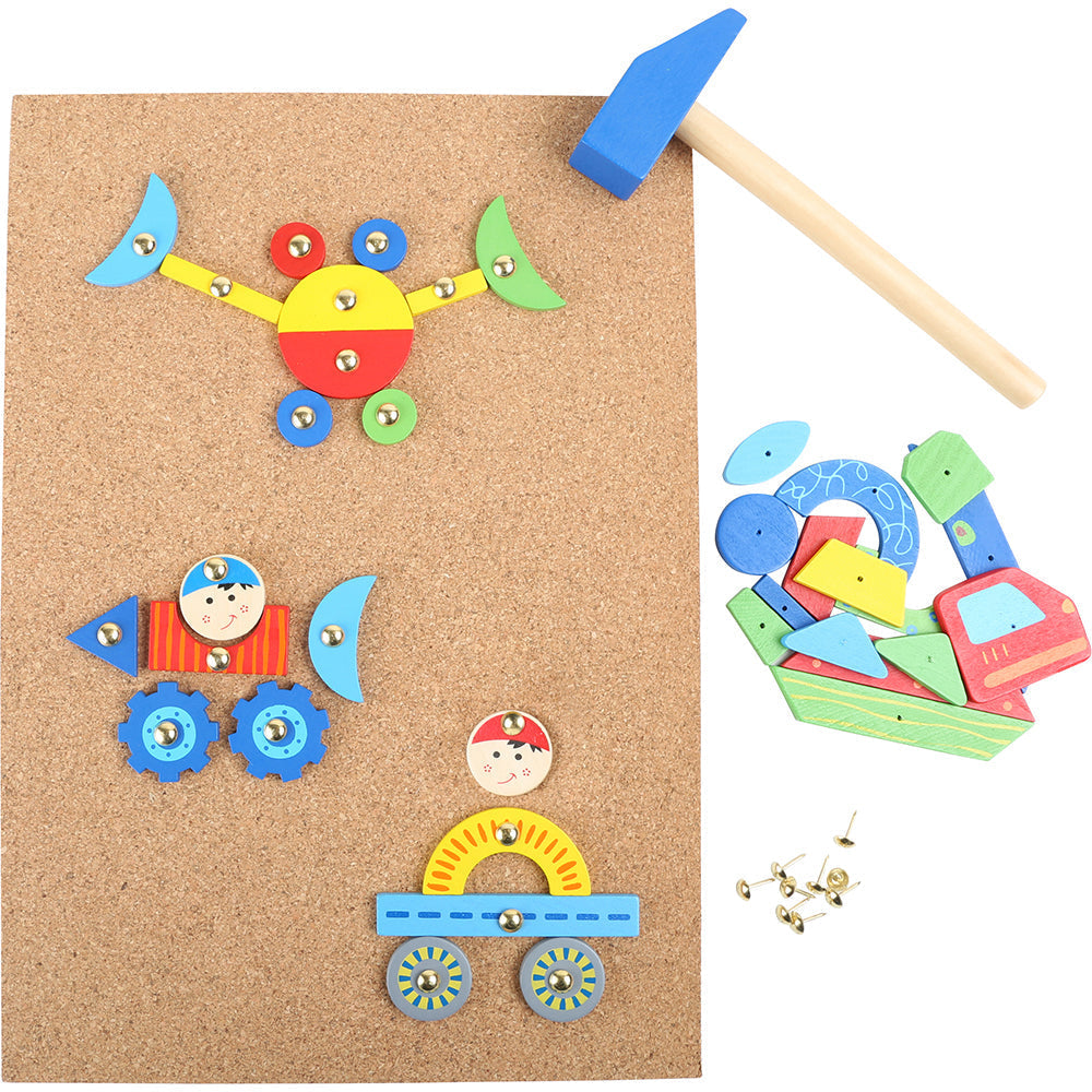 Bunte Holzpuzzleteile werden auf einem Korkbrett angeordnet, daneben liegen kleine Holzhämmerchen und Reißzwecken.