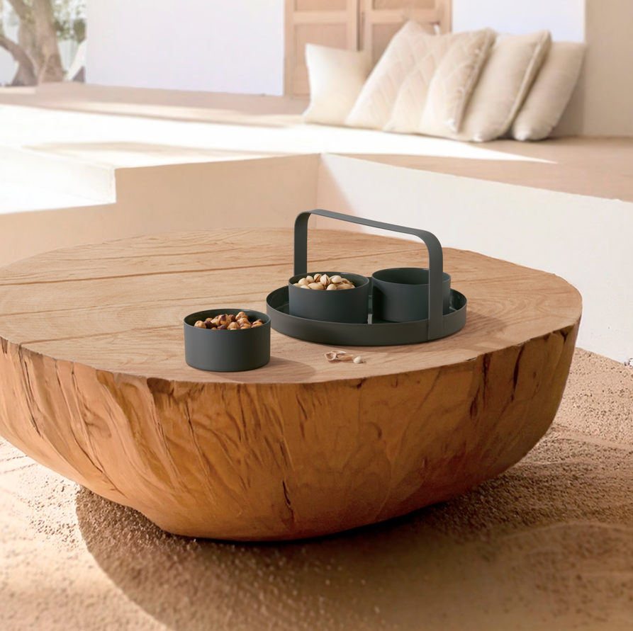 Runder Couchtisch aus Holz mit dem PHILIPPI Snackset CLARA – drei kleinen schwarzen Schüsseln mit Snacks – darauf; Schiefergrün-Kissen im Hintergrund.