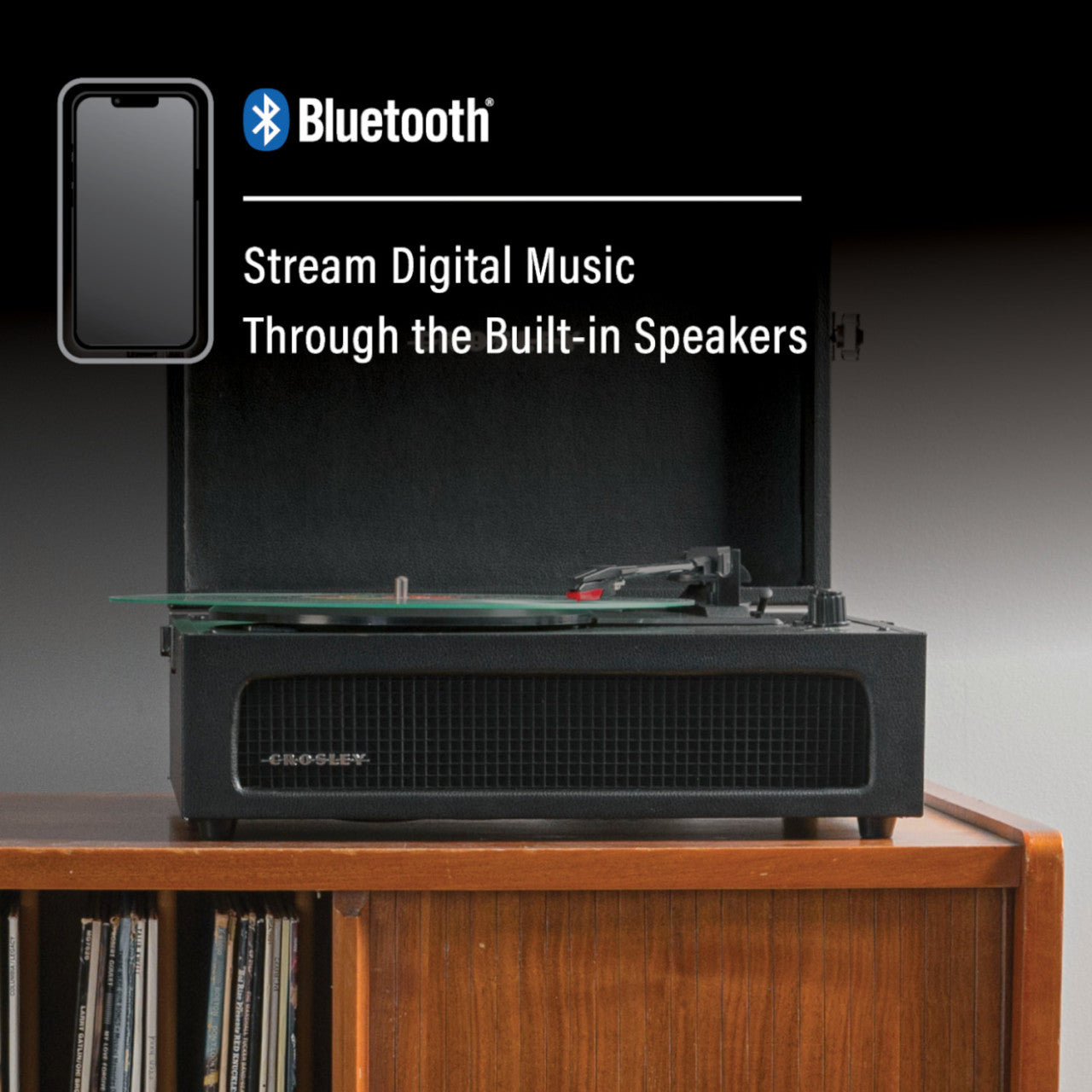 Ein Crosley Bluetooth Voyager Plattenspieler auf einem Holzregal mit Text über das Streaming von Musik an die integrierten Bluetooth-Lautsprecher und Unterstützung für 3 Geschwindigkeiten.