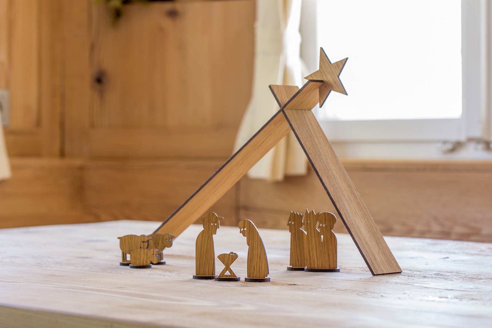 Minimalistische HOLZKRIPPE SIMPLY CHRISTMAS-Krippe aus Eichenfurnier mit Stern, Maria, Josef, Jesuskind, Hirte und Tieren, elegant auf einem Tisch angeordnet.