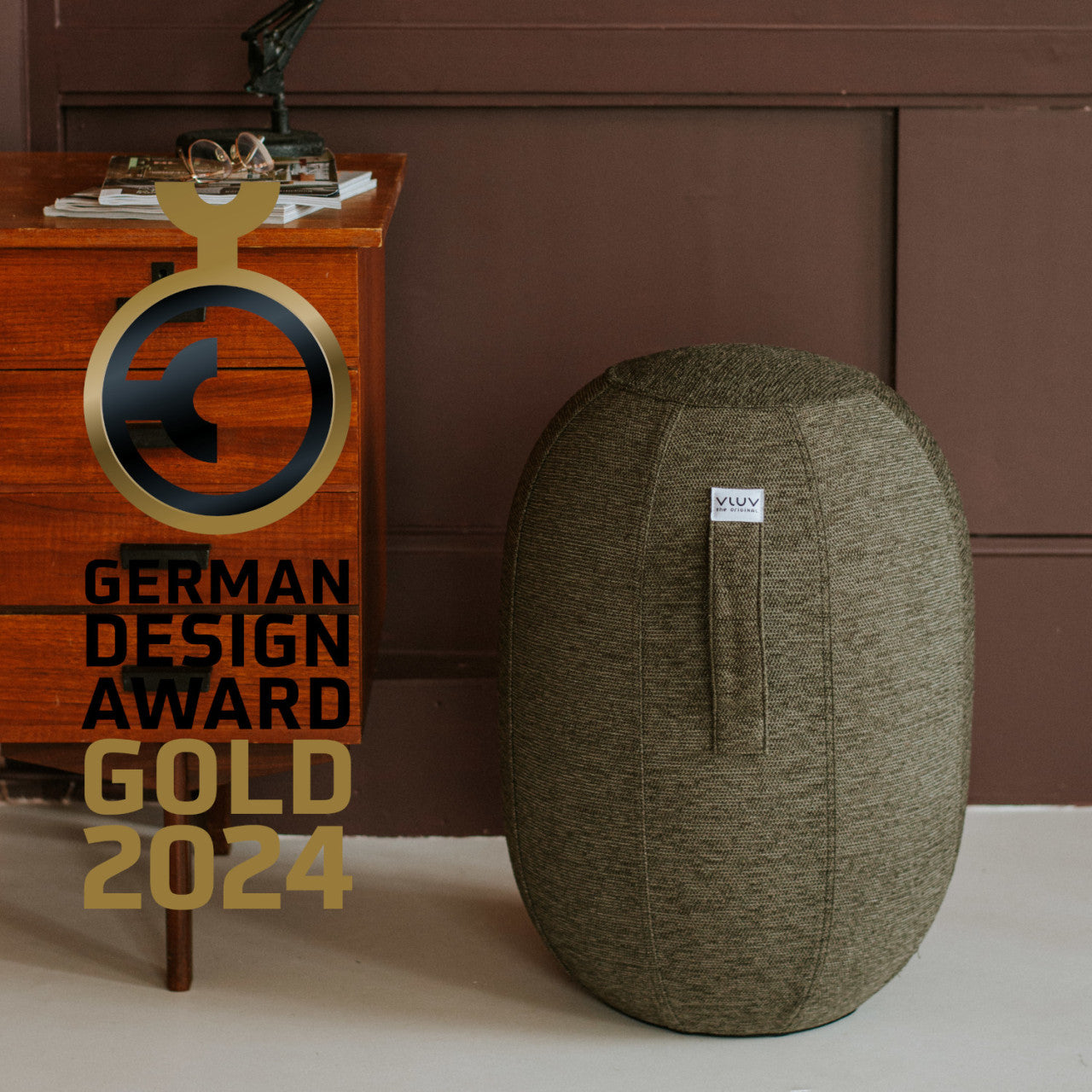 Grauer Balancehocker KAPSUL STOV an einem Nachttisch aus Holz; Gold Award 2024.
