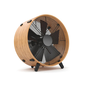 Ein moderner elektrischer Ventilator mit Holzrahmen und schwarzen Ventilatorflügeln, der auf drei schwarzen Beinen steht und einen eleganten Bambus-Ring aufweist, isoliert auf weißem Hintergrund.