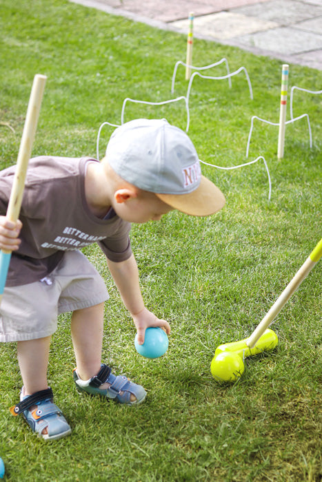 Kind genießt Krocket Spiel für Kinder "Active" mit Schlägel und bunten Bällen.