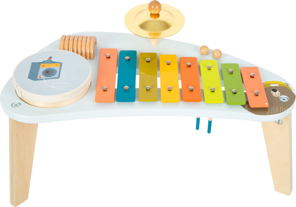 Farbenfroher Musiktisch aus Holz mit Xylophon, Becken, Trommel und anderen Schlaginstrumenten auf weißem Ständer für endlose Klang-Erfahrungen.