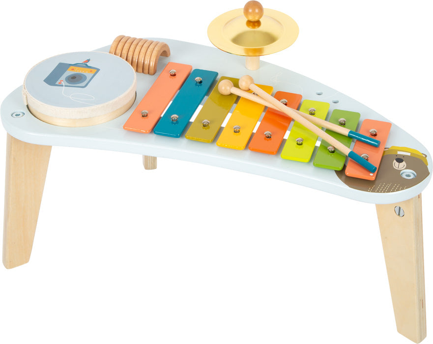 Kindermusiktisch mit Holz-Xylophon, Trommel, Becken und Stöcken auf einem kleinen Tisch – perfekt für spielerische Klang-Erfahrungen.
