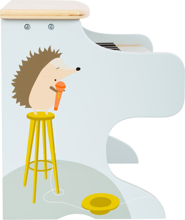 Cartoon-Igel hält ein Mikrofon auf einem Hocker, gemalt auf der Seite eines hellblauen elektronischen Holzklaviers, mit kindgerechten Motiven, perfekt für musikalische Früherziehung.
