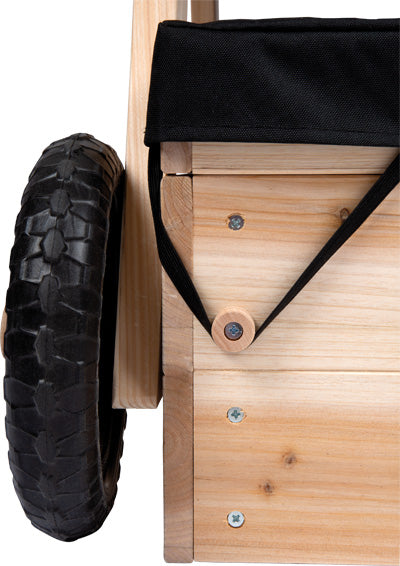 Nahaufnahme eines Holzwagens mit schwarzem Stoffbezug, Gummirädern und sichtbaren Schrauben – perfekt zum Transportieren von Spielzeug zum Sandkasten oder rund um die Kindersitzgruppe.