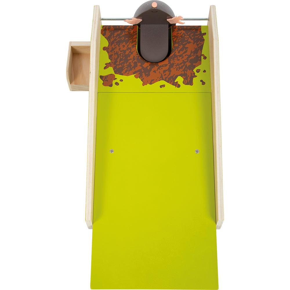 Draufsicht auf einen Spielzeugmaulwurf, der aus einem Loch auf einem grün-braunen Kinderspielbrett mit Holzseiten herausspringt.