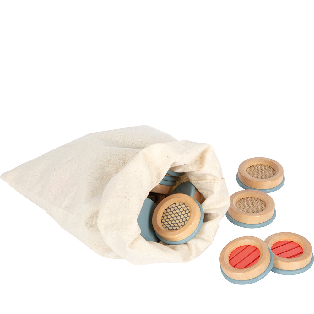 Stoffbeutel mit herausquellenden runden Holzplättchen, teilweise mit Rot- oder Gittermuster – ein charmantes taktiles Gedächtnisspiel aus der Sensory Produktlinie.
