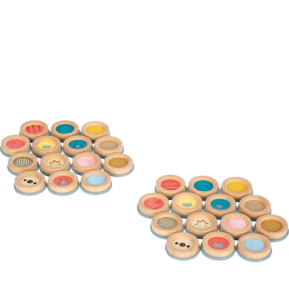 Zwanzig hölzerne taktile Sensorikscheiben aus der Sinnesspiel Sensory Produktlinie weisen verschiedene Farben, Texturen und Muster auf und sind in zwei Gruppen angeordnet, um ein einzigartiges taktiles Gedächtnisspiel-Erlebnis zu ermöglichen.