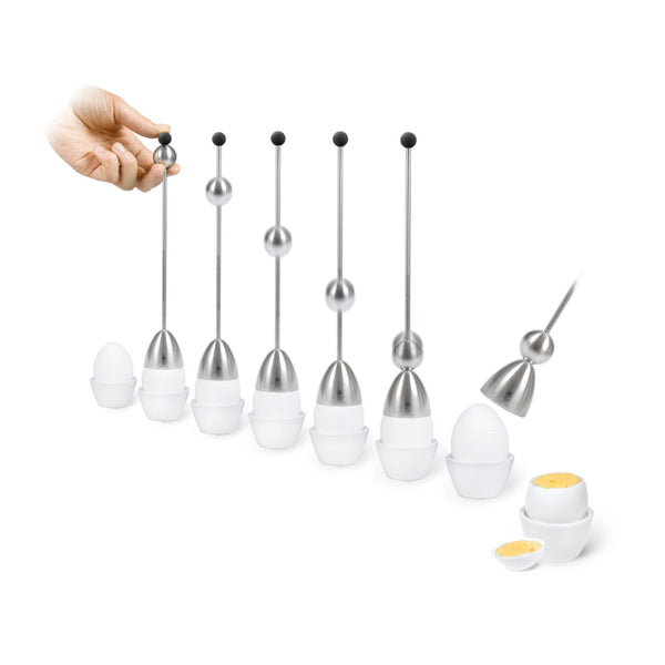 Eine Hand verwendet ein Eierköpferwerkzeug (Eierschalensollbruchstellenverursacher) aus Edelstahl, um die Deckel von weichgekochten Eiern in weißen Eierbechern aufzuschlagen.