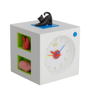 Weißer Kinderwecker in Würfelform mit schwarzer Katzenfigur obenauf, Spieltieren in Seitenfächern und lustigen Tierstimmen für ein fröhliches Aufwachen.
