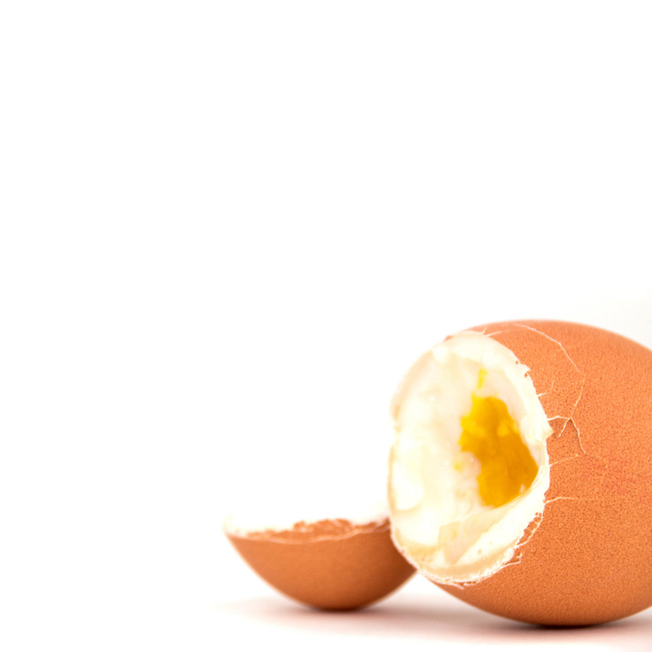 Ein braunes, hartgekochtes Ei, dessen Deckel aufgeschlagen ist, sodass das gekochte Eigelb und Eiweiß im Inneren zum Vorschein kommen – genau wie die perfekt gekochten Eier, die Sie mit smarte PiepEier erhalten.