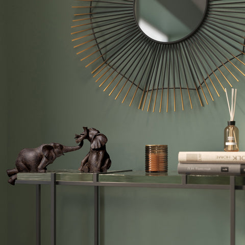 Zwei Deko-Elefanten aus Polyresin stehen auf einem Tisch unter einem runden Spiegel mit Goldakzenten – ein stilvoller Hingucker für jedes Zuhause.