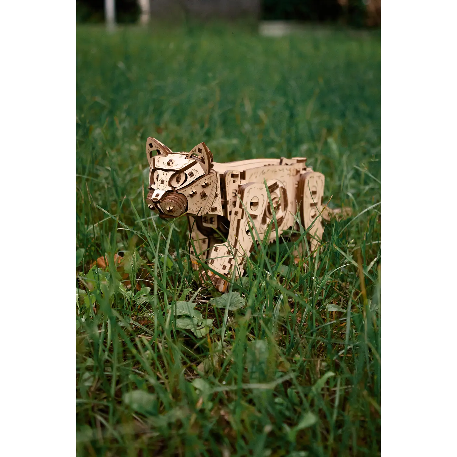 3D-Holzpuzzle Mechanische Katze, natur steht im hohen grünen Gras draußen.