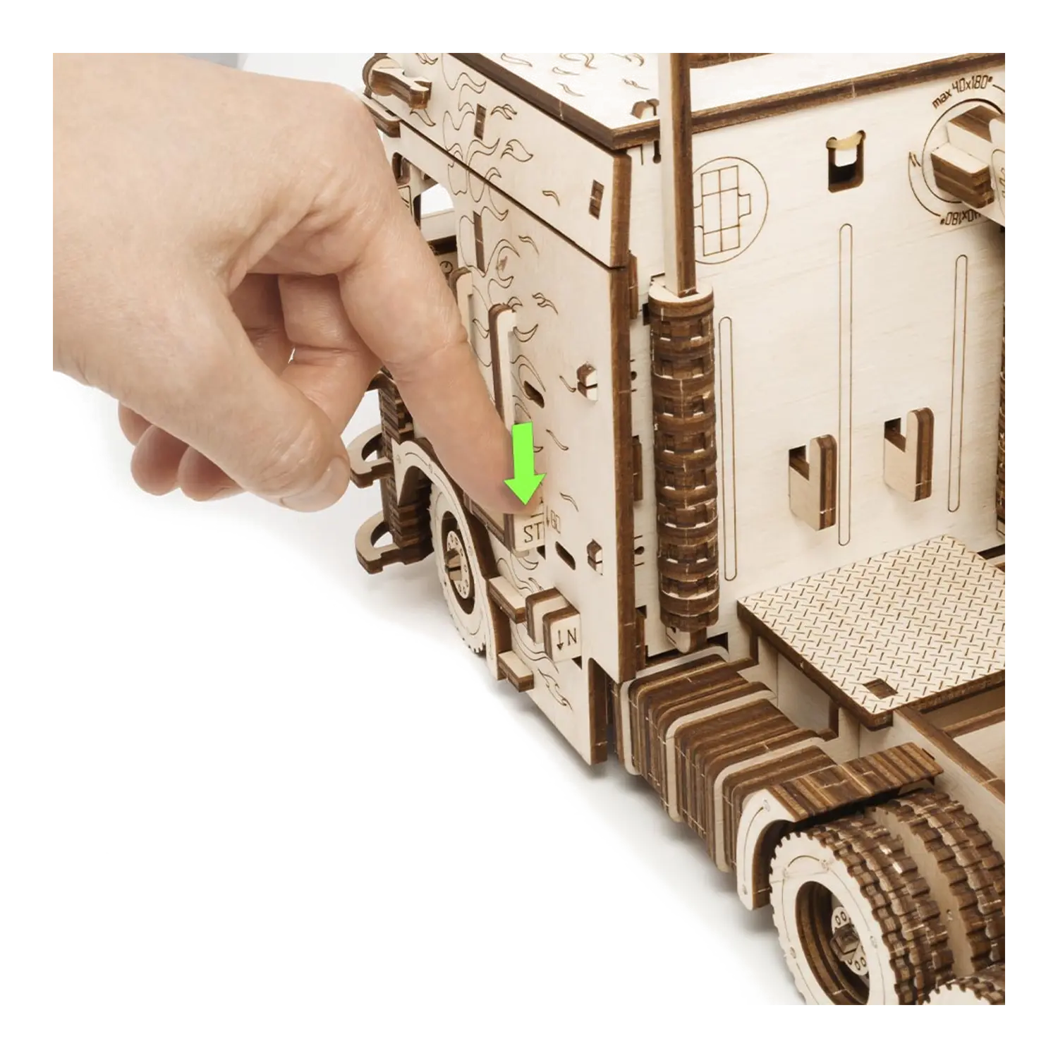 Eine Hand drückt einen Schalter an einem 3D-Holzpuzzle Road King LKW mit Container mit einem grünen Pfeil.