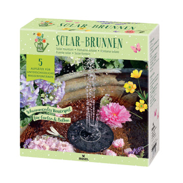 Karton für einen Solar-Brunnen-Bausatz, der als Gartendeko im Freien mit Blumen und Wasser dargestellt ist und in Deutsch und anderen Sprachen beschriftet ist.