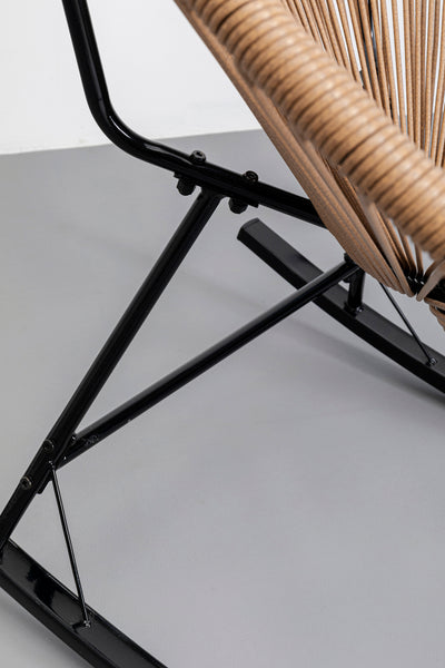 Nahaufnahme eines modernen Stuhls im Acapulco-Design mit schwarzen Metallbeinen und hellbraunem geflochtenem Sitz auf grauem Boden.