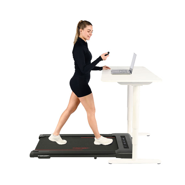 Eine Frau in sportlicher Kleidung geht auf einem Laufband und benutzt einen Laptop auf einem höhenverstellbaren Tisch.
