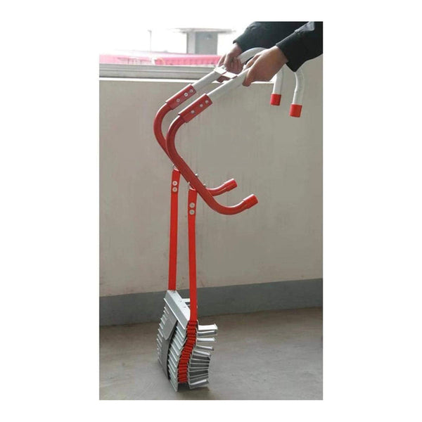 Eine Person hält mit beiden Händen ein Hebewerkzeug  das an mehreren gestapelten Ziegeln befestigt ist; das Werkzeug hat rote Griffe und Metallarme.
