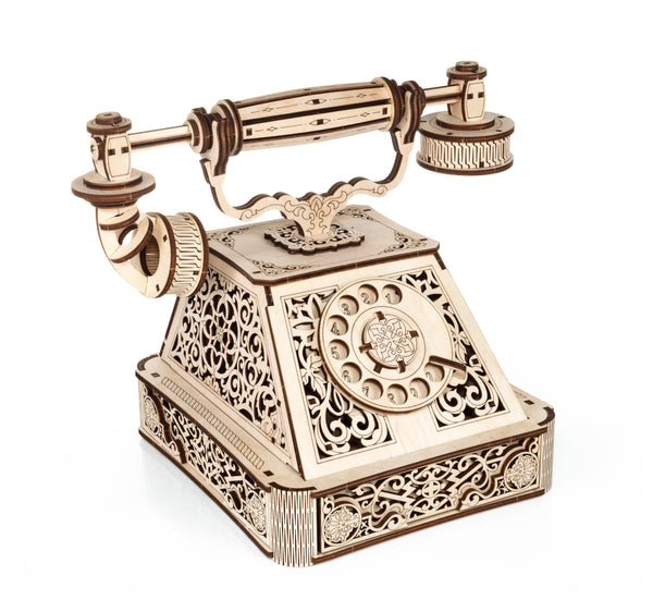 Ein detailliert geschnitztes Modell eines antiken Telefons aus Holz mit einem Wählscheiben-Zifferblatt und einem Hörer  reich verziert mit filigranen Mustern.
