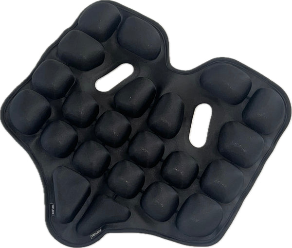 Ein schwarzes  gepolstertes Sitzkissen mit erhabenen  abgerundeten Noppen und zwei länglichen Schlitzen in der Mitte.
