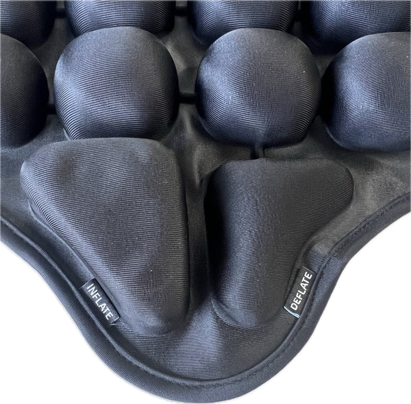 Nahaufnahme eines schwarzen  gepolsterten Sitzkissens mit mehreren runden  aufblasbaren Kammern  die jeweils mit "INFLATE" und "DEFLATE" beschriftet sind.
