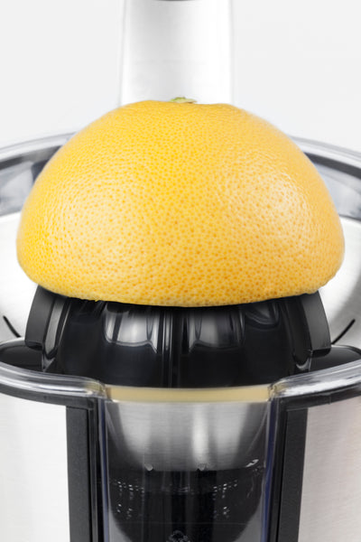 Eine halbe Grapefruit wird in einer elektrischen Zitruspresse entsaftet.

