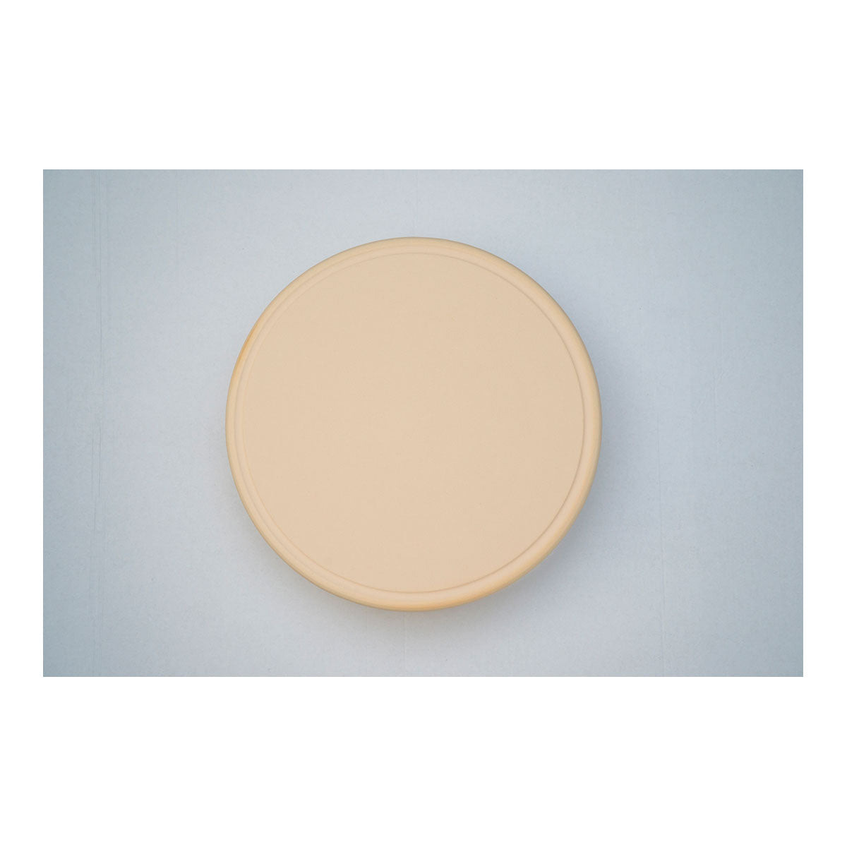 Eine runde beige-farbene Platte auf einem blauen Hintergrund.