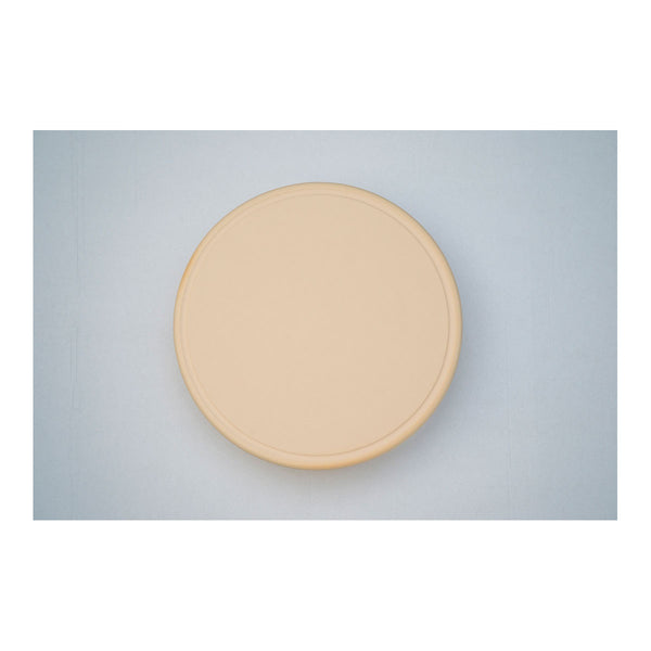 Eine runde beige-farbene Platte auf einem blauen Hintergrund.