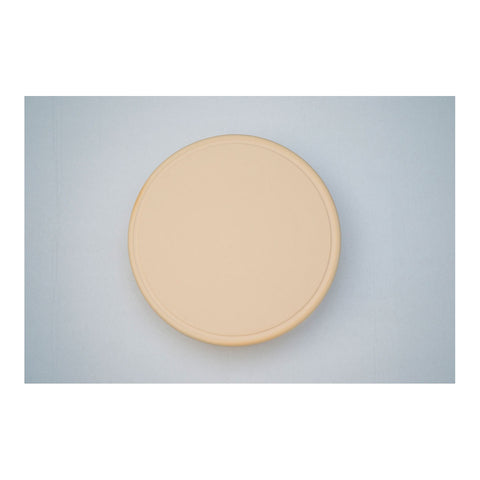 Eine runde beige-farbene Platte auf einem blauen Hintergrund.