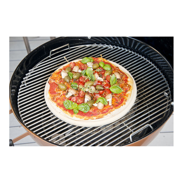 Eine Pizza mit Tomatensoße  Mozzarellastücken  Basilikum und Tomatenscheiben liegt auf einem heißen Grill.

