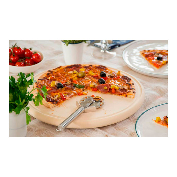 Eine Pizza mit frischem Basilikum und buntem Belag liegt auf einem dekoriertem Tisch. Daneben liegt ein Pizzaschneider