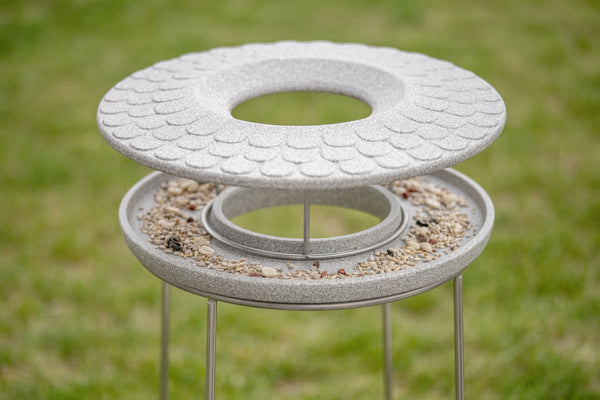 Zwei moderne Vogelhäuschen mit silbernen  konischen Dächern sind abgebildet  wobei das linke auseinandergebaut und das rechte vollständig montiert gezeigt wird.
