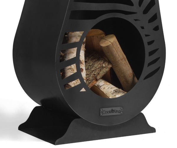 Ein schwarzer  dekorativ gestalteter Kaminholzständer aus Metall mit einem ovalen Sichtfenster  das mehrere Holzscheite zeigt.
