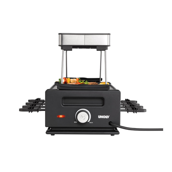 Ein elektrischer Tischgrill von Unold mit Temperaturregler und mehreren kleinen Pfännchen an den Seiten  auf dem Grill sind Lebensmittel zu sehen.
