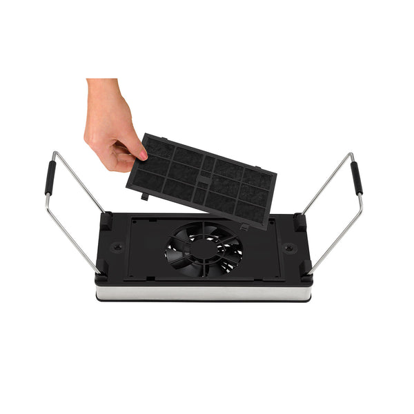 Hand setzt einen rechteckigen Aktivkohlefilter in die abnehmbare Dunstabzugseinheit eines Raclette-Geräts mit integriertem Ventilator ein.