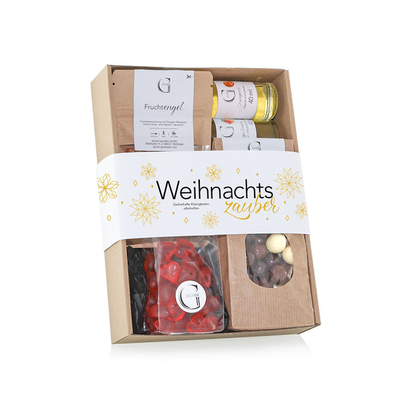 Eine Geschenkbox mit der Aufschrift "Weihnachtszauber" enthält verschiedene Leckereien  darunter eine Flasche  eine Packung Gummibärchen und Schokoladendragees  schön verpackt in einem Karton mit festlichem Design.
