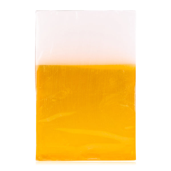 Ein rechteckiges Stück Seife mit einem transparenten  gelben unteren Bereich und einem undurchsichtigen weißen oberen Bereich.
