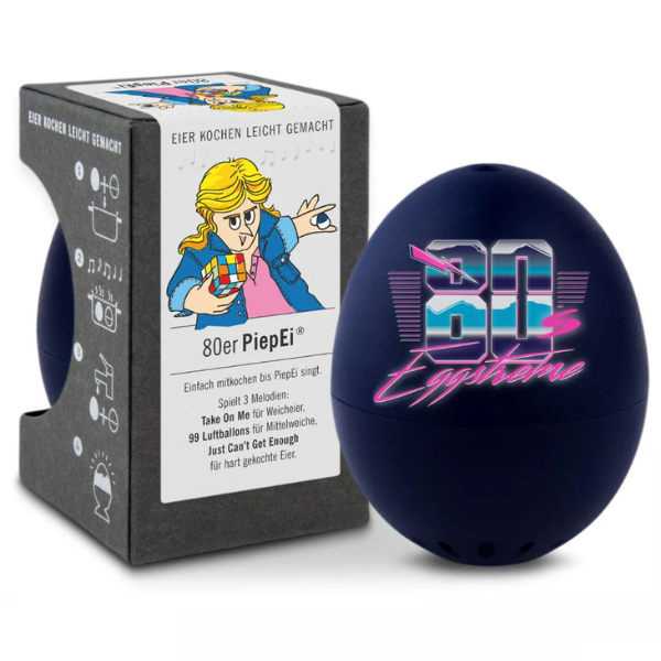 Eine dunkelblaue Eieruhr mit der Aufschrift „80s Eggstreme“ steht neben ihrer Schachtel, auf der ein Cartoon im 80er-Jahre-Stil mit einem Zauberwürfel abgebildet ist – damit gelingen Ihnen jedes Mal perfekt gekochte Eier.