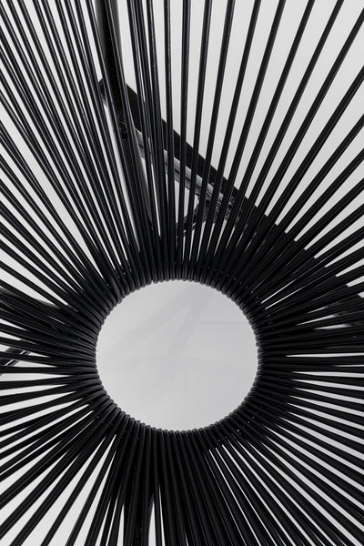 Schwarze radiale Speichen bilden ein kreisförmiges Acapulco-Designmuster mit offener Mitte auf weißem Hintergrund, das an einen stilvollen Outdoor-Stuhl erinnert.